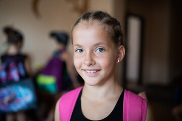Portrait of smiling girl gymnast with backpack in sports camp	
