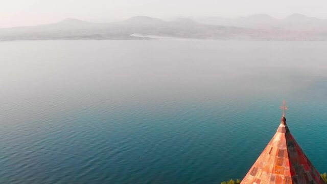 Close up view golden cross on top church dome with scenic lake landscape outdoors. Sevanavank armenia church