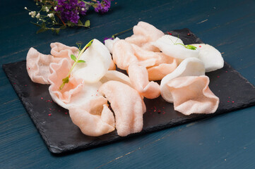 pink and white shrimp chips on a black stone