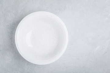 White empty ceramic plate on gray concrete or stone background.