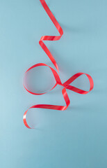 red gift wrapping tape in the shape of Christmas tree against pastel blue background. Minimalism