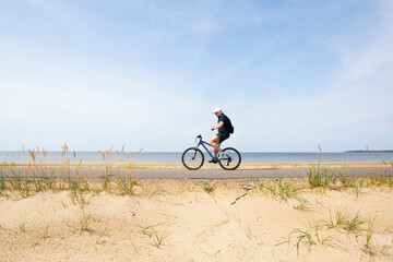 Fototapeta na wymiar A cyclist rides on an asphalt path along the sea