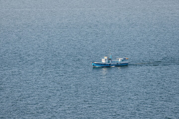 Naklejka premium Ferry boat or fishing ship transporting passengers on Lake Sevan in Armenia. Water cruise and tours concept