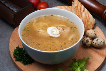 chicken soup with noodles and quail egg on a wooden board