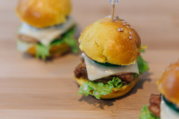 Three delicious chicken cheese  hamburgers on wooden board