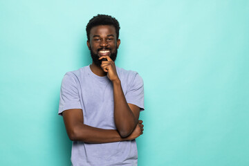 Young african man with hands on chin isolated on turquoise background