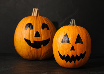 Pumpkins with drawn spooky faces on dark background. Halloween celebration