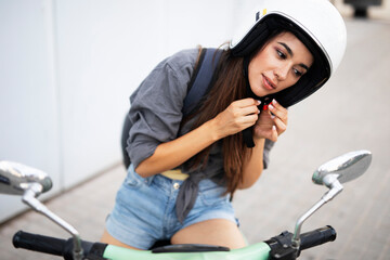 Naklejka na ściany i meble Beautiful woman getting ready for a ride on scooter. Beautiful happy lady having fun outdoors..