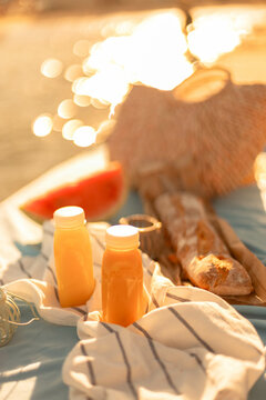 Plastic bottles of freshly squeezed juice on the pier on a sunny day. Romantic picnic by the sea.