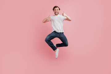 Fototapeta na wymiar Full size photo of young happy excited smiling positive man jump show thumb-up like cool advert isolated on pink color background