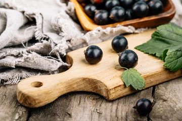 Foto op Plexiglas Fresh black currant. A handful of berries on a wooden table © fusssergei