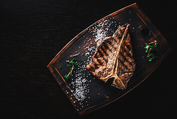 Grilled T-bone Steak on bones on wooden board on dark background