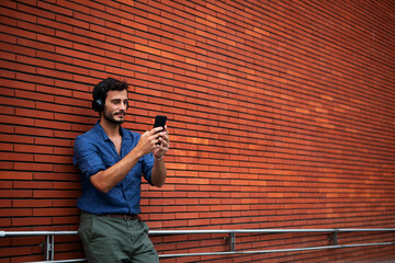 Young man listening to music. Urban fashion man with headphones enjoying the city.