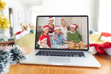Fototapeta na wymiar Smiling multi generation caucasian family in santa hats on laptop christmas video call screen