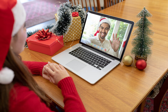 Caucasian woman in santa hat making christmas laptop video call with smiling biracial man