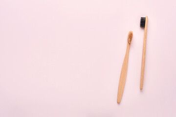 Teeth hygiene and oral dental care products on pink color background with copy space. Eco-friendly bamboo toothbrushes and cotton flowers. Flat lay, top view composition, mockup. Morning concept.