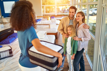 An African American woman salesperson consultant consults a young family by showing samples of...