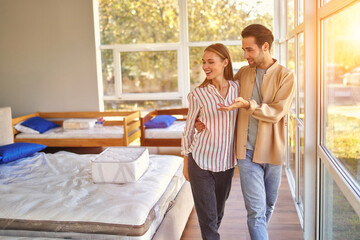 A young couple is choosing bedding at a bed, mattress and pillow store. Everything for a...
