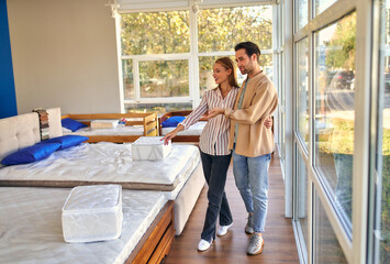 A young couple is choosing bedding at a bed, mattress and pillow store. Everything for a comfortable sleep.