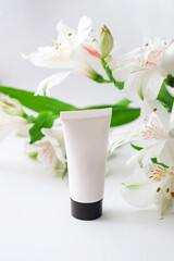 moisturizing hand cream in a white case with a black lid on a background of alstroemeria