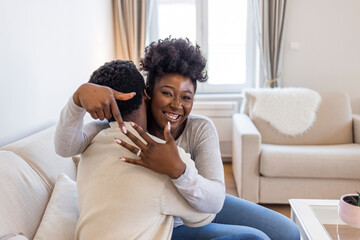 Man with engagement ring proposing marriage to girlfriend in new house, they are kissing with smile. Amazed African American couple getting engaged. She said yes!