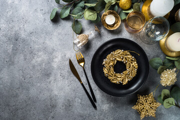 Christmas table setting with eucalyptus leaves and golden decorations. Top view at stone table.