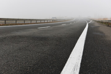 Asphalt road with a white stripe in the fog.