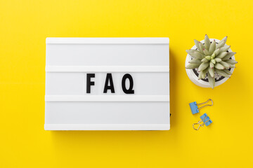 FAQ word on lightbox on yellow background, frequently asked questions concept