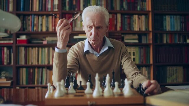 Serious grandmaster thinking over chess composition, sitting in library, hobby