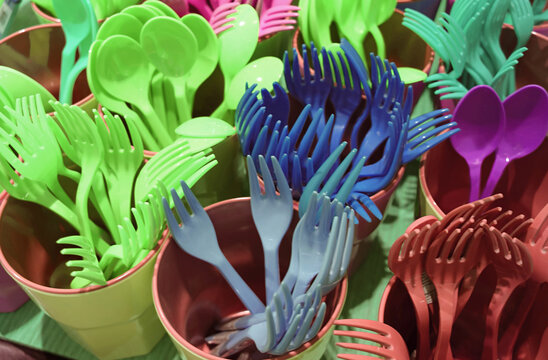 Groups of vivid green and blue plastic-ware spoon and forks in plastic cups
