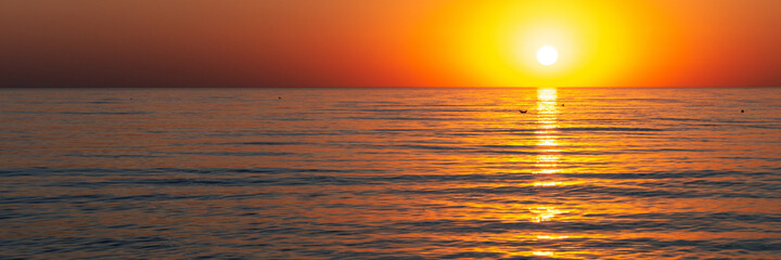 Fototapeta na wymiar sun goes down by the sea panorama