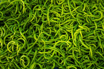 Close-up on a shelf with green peppers in the market.