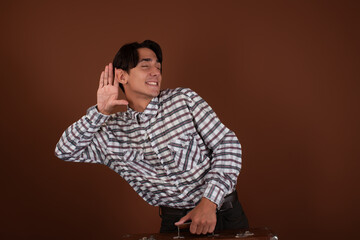 Young and funny guy with a suitcase on a brown background. The man got ready to go on vacation.