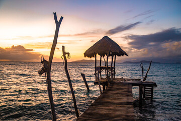 Sunset over wooden beach bar in sea and hut on pier in koh Mak island, Trat, Thailand