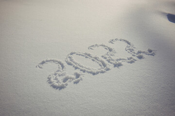 Drawing on white snow in sunlight. New Year's date, figures 2022, close-up.