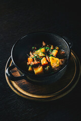 Goulash. Vegetable rague with meat, eggplant, pepper, potato and carrot in black bowl on dark wooden background