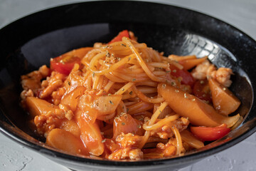 Spaghetti with tomato sauce, chicken and sausage in black plate top view. Flat lay.