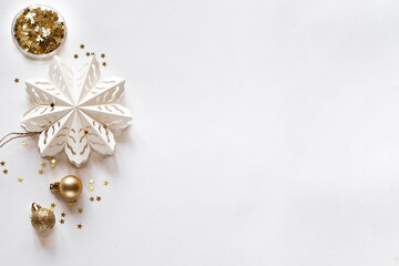 White origami snowflake and gold decor on white background, new year card, top view