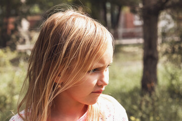 portrait in profile of a child girl blonde 7 years old on the background of nature
