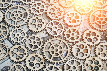 Gears different sizes against background hundred dollar bills, concept progress and economic growth.