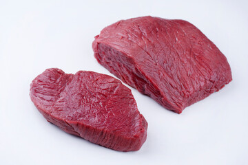 Raw dry aged bison beef rump steak slices offered as close-up on white background with copy space - free-form select © HLPhoto
