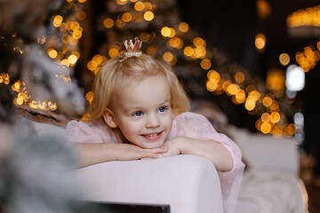 A cute charming girl smiles sincerely. The child is waiting for Christmas. Portrait of a child for...