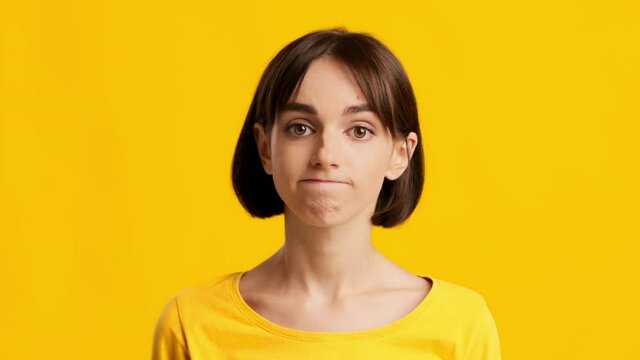 Clueless Young Female Making Shoulder Shrug Over Yellow Background