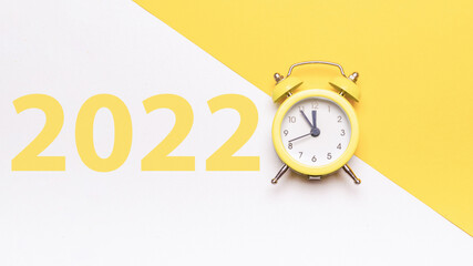 Christmas time 2022. Retro style yellow clock in happy Christmas midnight. Countdown to new year on happy xmas yellow background. Xmas greeting card. Happy New Year.