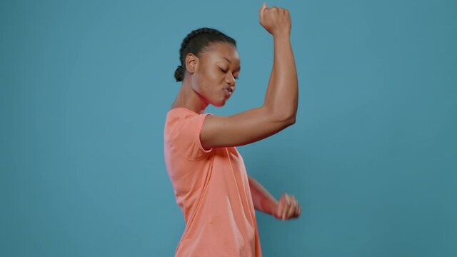 Sporty woman flexing trained arm muscles in front of camera. Athletic person showing strong musculature, advertising fitness and weight lifting. Young woman with fit masculine biceps
