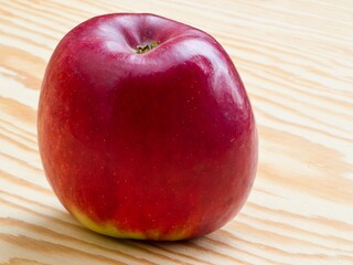 Ripe red apple lying on a wooden table top.