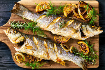 Roasted sea bass on a black wooden table, close-up