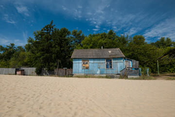 View across the beach to an old wooden house near a green forest. Relax in nature. summer landscape