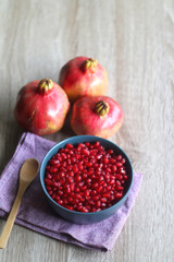 Bowl filled with pomegranate seeds and pomegranate fruit on a table. Selective focus.