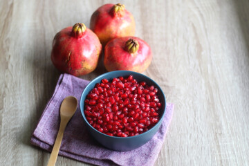 Bowl filled with pomegranate seeds and pomegranate fruit on a table. Selective focus.